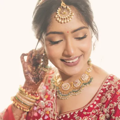 More than a bride, an emotion. Our beautiful bride Saloni glows in a traditional gold necklace with green beads and a matching maang tikka.