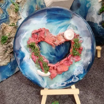 A custom "Lover's Island" resin piece. The heart-shaped island is surrounded by swirling blue resin waves, making it a perfect personalized gift to capture a romantic memory.