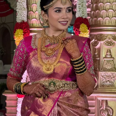 A radiant bride on her special day. This look features a soft glam finish that feels like a gentle breeze, perfectly complementing her pink silk saree and the divine temple setting.