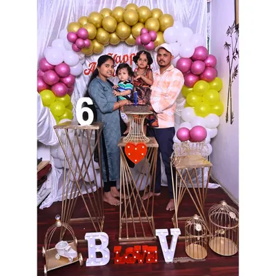 A happy family celebrating their 6th anniversary with a decoration I designed. The setup includes a balloon arch, modern gold stands, and light-up letters for their initials.