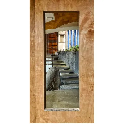 A staircase viewed through a door frame, appearing like a framed piece of art. This composition highlights the raw beauty of the stone steps and the massive boulder at their base, celebrating the power of natural materials.