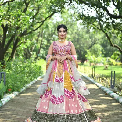A stunning full-view of a multi-color patchwork lehenga. This design combines panels of pink, yellow, and grey with traditional bandhani and mirror work for a truly unique festive look.