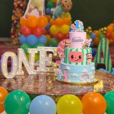 A vibrant two-tier Cocomelon cake, perfect for a first birthday party, set up beautifully at the venue.