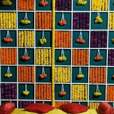 This is a classic mehandi backdrop with a twist. The checkered wall is filled with panels of orange, yellow, and purple marigolds, with delicate floral hangings that add a touch of elegance to the vibrant setup.