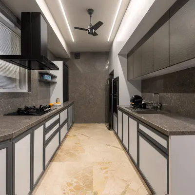 This sleek, parallel kitchen in a modern loft features a monochromatic theme with quartz countertops and minimalist lighting. The design maximizes functionality and maintains a clean, uncluttered aesthetic, perfect for contemporary living.
