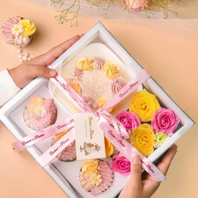 A beautiful bakery gift hamper with a mini cake, cupcakes, and fresh flowers, showcasing my skills in product and gifting photography.