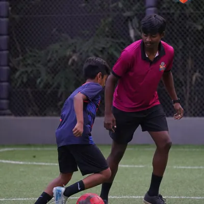 A coach provides detailed instructions to a player during a 1-on-1 session, focusing on defensive stance and positioning. This personalized feedback is key to rapid improvement.