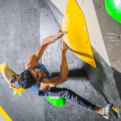 Bouldering is the ultimate full-body workout that feels more like play. Here, a climber stretches for a hold on a challenging overhang, engaging his core and upper body.