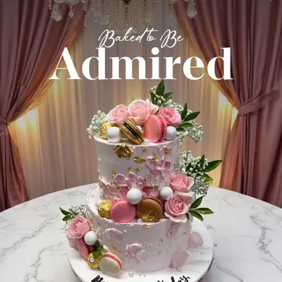 Baked to be admired. This exquisite two-tiered birthday cake is adorned with fresh roses and macarons, crafted with love and a touch of magic.