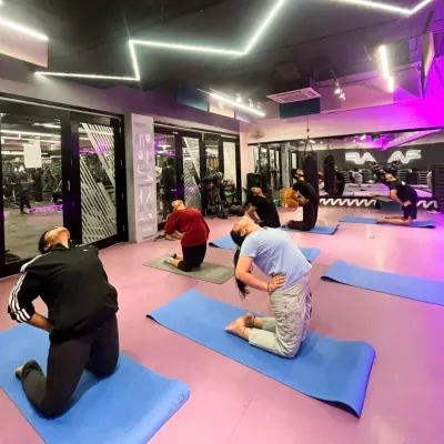 A group of members performs the Camel Pose (Ustrasana) during a yoga class. This image showcases the shared experience of stretching and opening up, guided by our instructor in the studio's ambient lighting.
