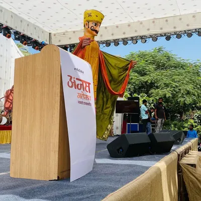A giant puppet of a Rajasthani man stands tall on stage during the Anjas Mahotsav. These figures are designed to be focal points for large events, adding a unique and traditional touch to any modern stage setup.