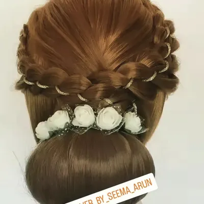 An elegant braided bun hairstyle, perfect for a reception or engagement. The delicate white flowers and glitter accents add a touch of glamour to this classic updo.