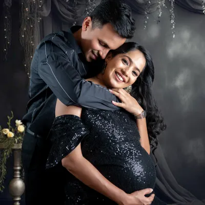 An intimate and happy moment between a couple during their studio session. The dark, elegant theme with a black sequin gown creates a glamorous feel.