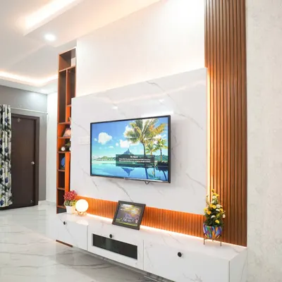 A bespoke floating entertainment unit that combines a marble-finish back panel with vertical wooden fluting for a touch of modern elegance. The design includes concealed storage and warm ambient lighting, creating a sophisticated and clutter-free focal point in the living room.
