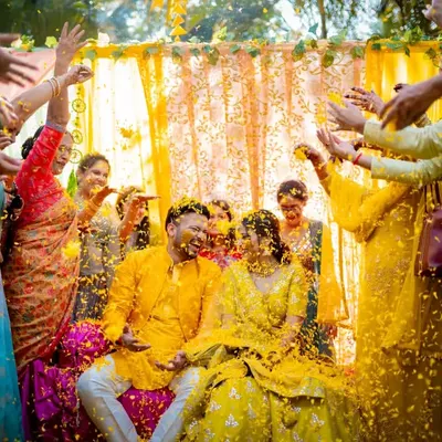 A joyous Haldi moment as the couple is showered with flower petals by their loved ones. We capture the peak of the celebration, full of energy and happiness.