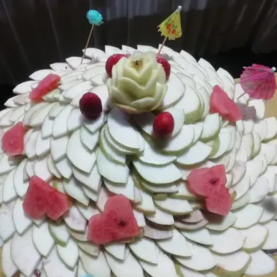 An artistic fruit arrangement featuring thinly sliced guava, watermelon hearts, and a beautifully carved apple rose. This display shows the creativity I bring to my fruit platters.
