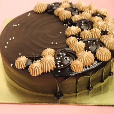 Our signature eggless chocolate cake is a top choice for celebrations. This design features a rich chocolate ganache drip and is elegantly topped with piped chocolate cream.