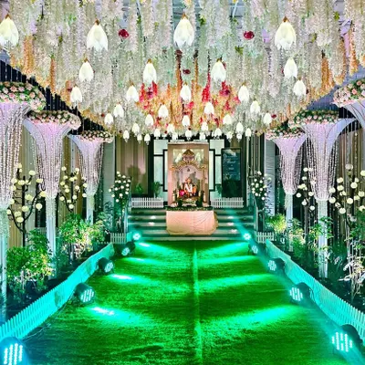 A classy and opulent reception entrance we designed. The pathway is lined with stunning pearl and crystal chandeliers hanging from the ceiling, leading to a Ganesha idol, creating a breathtaking first impression for guests.