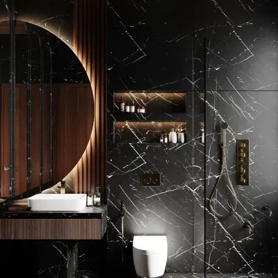This bathroom is a study in dark, moody luxury. We used floor-to-ceiling black marble with dramatic white veining, a backlit circular mirror, and warm wood accents to create a sophisticated and intimate retreat.