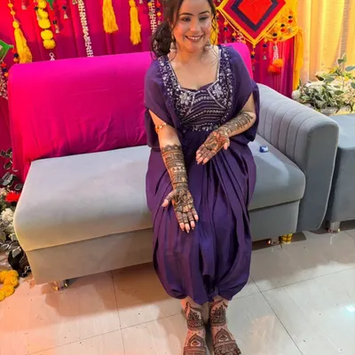 A full view of a happy bride with her complete bridal mehendi. The intricate designs on her hands and feet create a stunning, cohesive look.