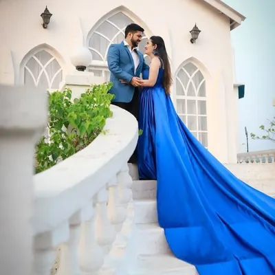 Create a cinematic moment with our pre-wedding shoot outfits. The groom looks sharp in a light blue suit, while the bride stuns in a royal blue gown with a dramatic, flowing train.