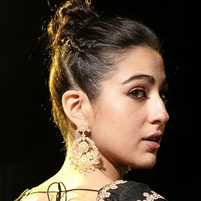 A close-up of the handcrafted 18k gold Chandbali earrings worn by Sara Ali Khan. This view highlights the intricate filigree work and the delicate pearls that dangle from the classic crescent moon shape.