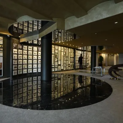 The Gala showroom, where a central black marble disc reflects the intricate display of architectural hardware on the walls. The design uses curves and dramatic lighting to create an immersive and high-end retail experience.