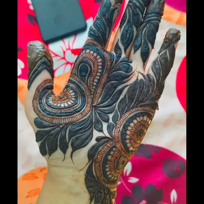 A finished Khaliji design with the henna paste applied. This style is known for its bold, dark-staining elements and the beautiful use of negative space on the skin.