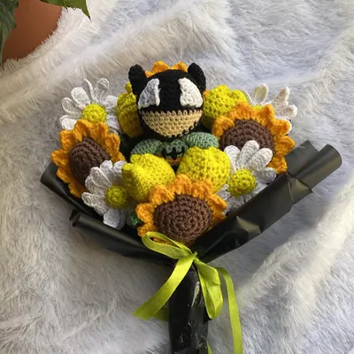 A full and vibrant Batman-themed bouquet. This custom order combines sunflowers, daisies, and yellow tulips with a Batman amigurumi nestled in the center.