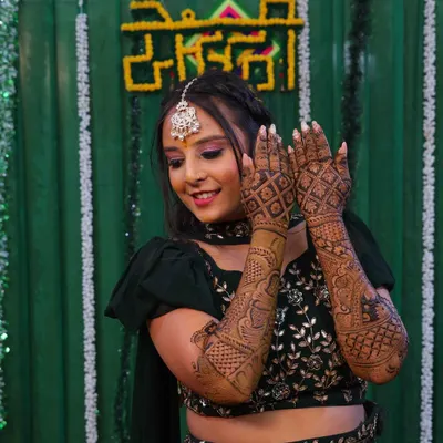 A happy bride showing off her full-arm mehndi. The design features a heavy jaal pattern on the back of the hands, perfect for wedding photos.