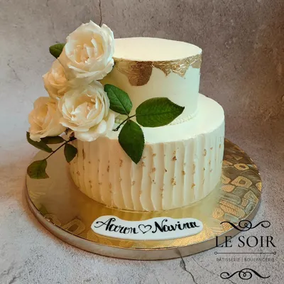 This elegant two-tier cake was for a beautiful wedding celebration. I used a combination of textured buttercream on the bottom tier and a smooth finish with a gold leaf accent on top, all brought together with fresh white roses.