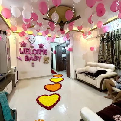 A heartwarming welcome home decoration for a baby girl. The setup fills the living room with pink and white ceiling balloons and features a beautiful pathway of marigold flower hearts leading into the home.