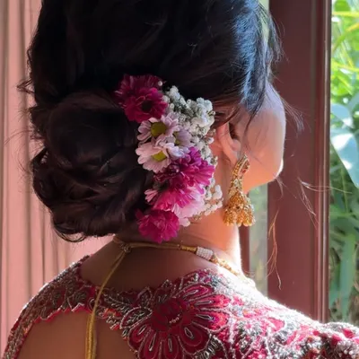 A beautiful detail shot of a classic bridal bun. This hairstyle features a voluminous, textured bun adorned with fresh baby's breath and colorful flowers, adding a touch of romance to the traditional look.