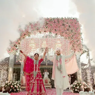 A fairytale moment as the newly married couple stands under a magnificent floral arch, showered with petals and surrounded by sparklers. This is the kind of grand, celebratory shot that defines a wedding day.