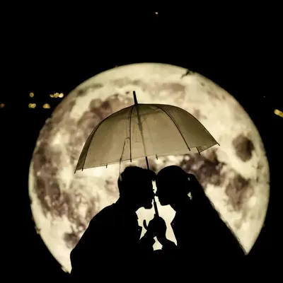 An iconic silhouette shot of a couple under an umbrella, perfectly framed by a giant, glowing moon. This is a highly creative and romantic concept that we love to execute.