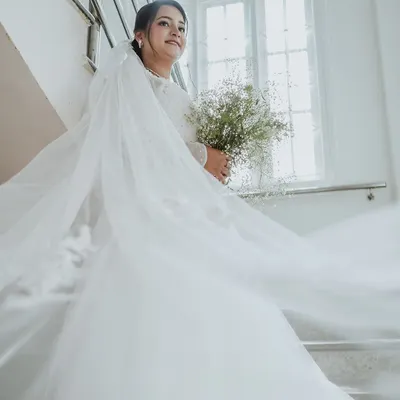 The bride looks ethereal in her flowing white gown and veil, holding a simple bouquet. This shot captures the classic elegance and dreamlike quality of a Christian wedding.