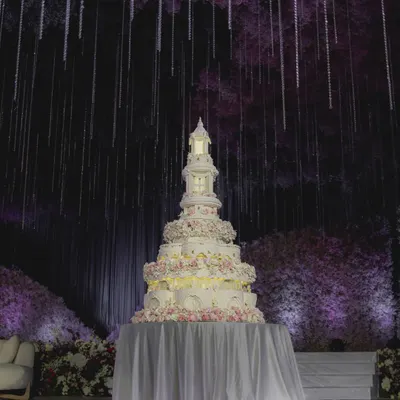 The full view of our 8-foot tall architectural masterpiece, set against a backdrop of hanging crystals. This cake was designed to command the room, with its illuminated tiers and incredible scale making it a focal point of the wedding reception.