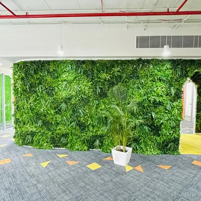 A large artificial vertical garden wall installed in a modern office space. It provides a huge splash of green with zero maintenance.