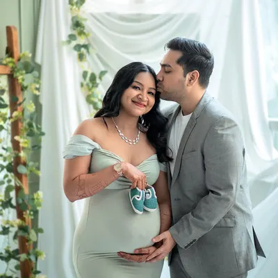 A sweet and symbolic portrait, with the parents-to-be holding up a tiny pair of shoes. This is a beautiful way to announce the coming arrival of their little one.