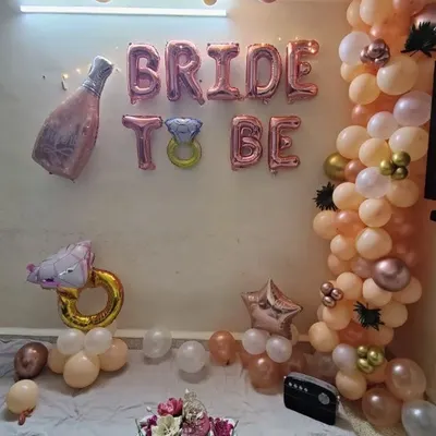 A complete 'Bride to be' decoration for a home party. This setup includes a rose gold and peach balloon garland with 'Bride To Be' foil balloons and other fun shapes.