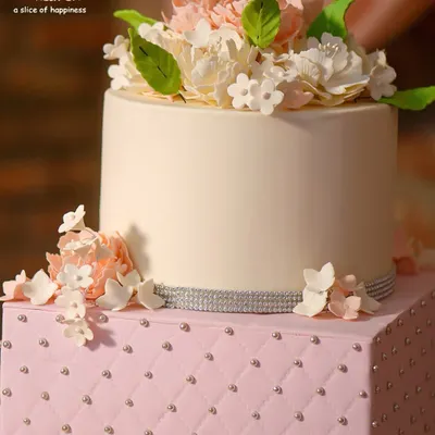 It's all in the details. This two-tiered custom cake features a sophisticated quilted design and handcrafted sugar flowers, perfect for an elegant engagement or anniversary celebration.