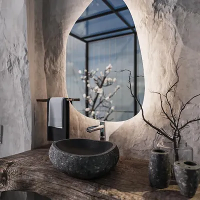 We designed this powder room to be a unique, immersive experience. It features raw, cave-like stone walls, a live-edge wood countertop, and a vessel sink carved from a single piece of stone, all illuminated by a modern backlit mirror.