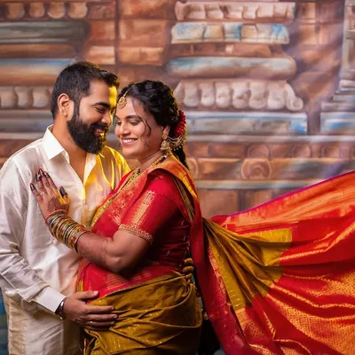 An intimate couple's portrait from a traditional seemantham session. The warm lighting and genuine smiles reflect the joy of this chapter, set against a backdrop that evokes the sanctity of a temple.