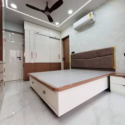 This master bedroom features a custom bed with a modern upholstered headboard and convenient bedside drawers. The false ceiling with cove lighting provides a soft, relaxing glow perfect for winding down.