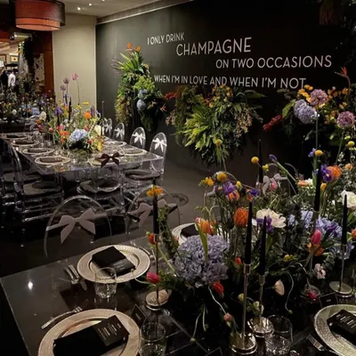 A breathtaking setup for an intimate sit-down dinner. The theme, "I only drink champagne on two occasions," sets a celebratory tone, with dramatic florals and elegant place settings.