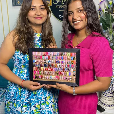 A proud instructor-student moment, showcasing the student's completed frame of diverse nail art designs.