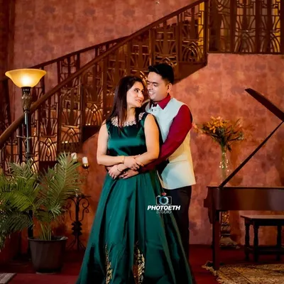 A truly elegant pre-wedding portrait in a grand, wood-paneled room. The chandelier, grand piano, and the couple's formal attire create a look of timeless luxury.