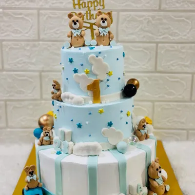 A grand three-tiered cake for a first birthday, decorated with adorable teddy bears, fluffy clouds, and stars. A perfect centerpiece for a memorable celebration.