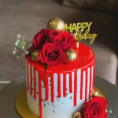 Red and florals can never go wrong. This elegant birthday cake features a bold red drip, fresh red roses, and gold sphere accents for a classic and luxurious look.