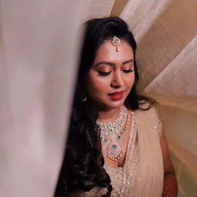A beautiful close-up portrait of the bride, her face softly lit, highlighting her elegant jewelry and makeup for the reception.
